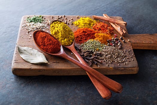 Colorful herbs and spices for cooking dishes. Indian and Asian spices On grey stone background closeup.