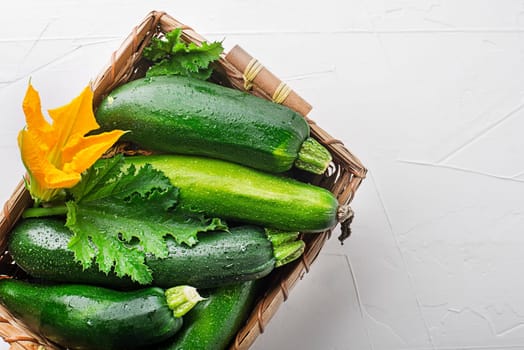 Basket of fresh vegetable crops with fresh zucchini on white background closeup