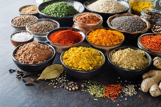 Colorful herbs and spices for cooking meal. Indian and Asian spices On grey stone background closeup