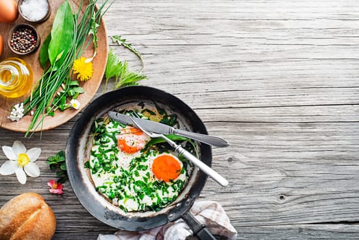 Fried eggs with fresh spring plants and herbs. Healthy spring food concept.