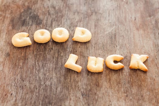 Good luck alphabet biscuit on wooden table, stock photo