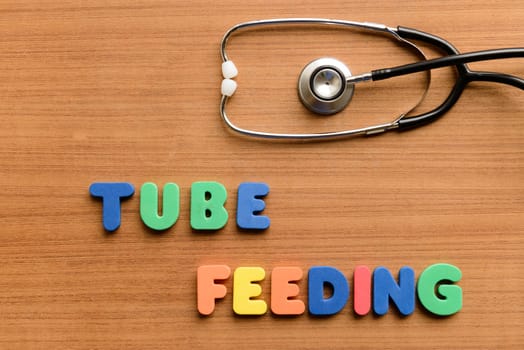 Tube feeding colorful word on the wooden background