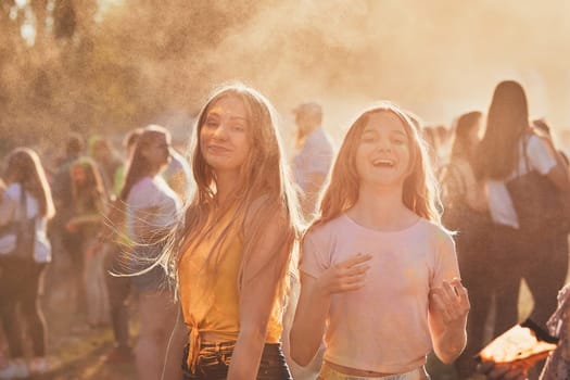 Portrait of happy smiling young girls with colorful paints on faces and clothes. Two friends spending time on holi color festival