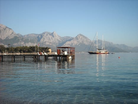 Kemer Antalia nice view of the sea. Beach Kemer Antalia with sand and mountains, the sea with the ship. Beautiful harbor near the sandy beach.