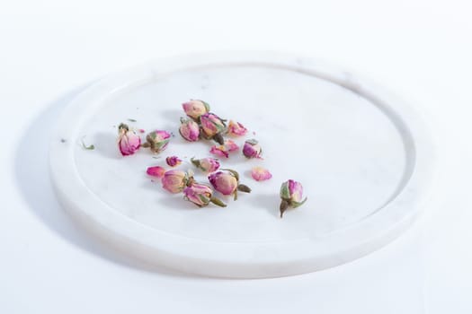 beautiful and pink small dried roses on a on a marble plate white background