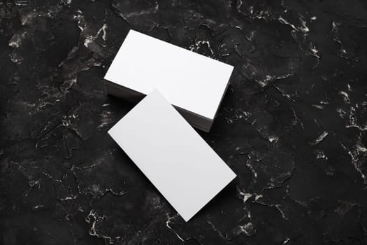 Photo of blank business cards on black plaster background. Mock-up for branding identity. Studio shot.