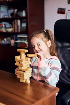 Little girl preschooler playing with wooden blocks toy building a tower. Concept of building a house