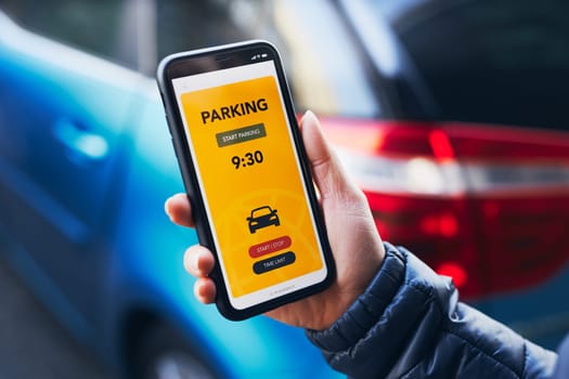 Woman using mobile parking app on smartphone. Driver using smartphone to pay for parking. Car park application on mobile phone. Convienience paying for parking using fast payment online. Mobile park service