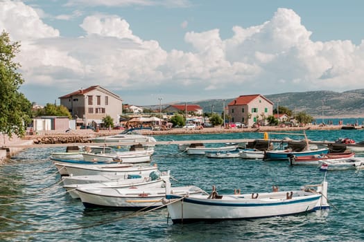 Many boats moored to the pier and shore. Town in the distant
