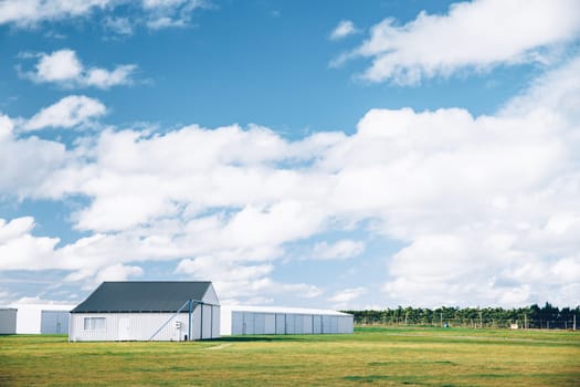 Steel barn on a farm with cloudy blue sky.