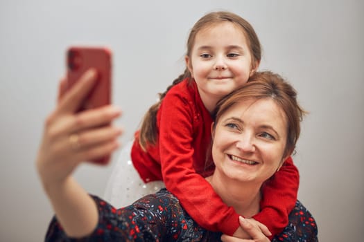 Mother with her little daughter making video call using mobile phone. Keeping distance. Woman and little girl talking with relatives. Cheerful family having fun taking selfie photo using smartphone. Connecting remotely with family