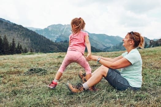 Little girl laying playing on grass enjoying summer day. Happy child playing in the field during vacation trip in mountains