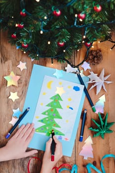 Girl drawing Christmas card with pine tree