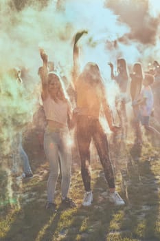 Portrait of happy smiling young girls with colorful paints on faces and clothes. Two friends spending time on holi color festival