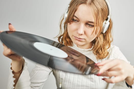 Young woman listening to music from vinyl record player. Playing music on turntable player. Female enjoying music from old record collection at home. Stack of analog vinyl records. Retro and vintage music style. Music Passion and hobby
