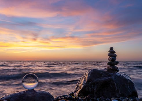 Stone pyramids and glass sphere on the dreamy Baltic Sea sand beach on Rügen for the spectacular sunset