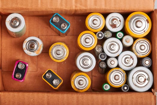Discharged batteries in cardboard box. Collecting used batteries to recycle. Waste disposal and recycling. Copy space for text
