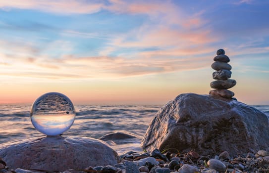 Stone pyramids and glass sphere on the dreamy Baltic Sea sand beach on Rügen for the spectacular sunset