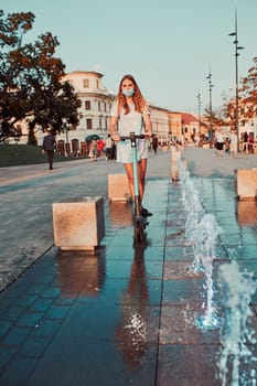 Young woman riding an electric scooter in the city center. Woman wearing the face mask to avoid virus infection and to prevent the spread of disease in time of coronavirus. Candid people, real moments, authentic situations