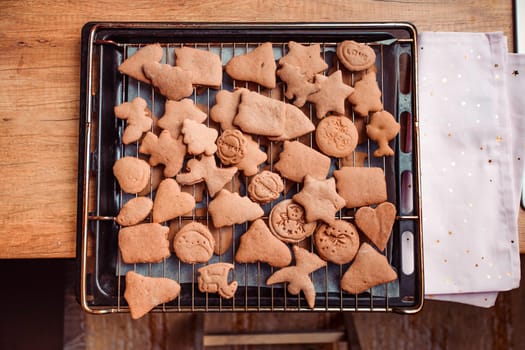 Baking Christmas cookies. Christmas gingerbread cookies in many shapes decorated with colorful frosting, sprinkle, icing, chocolate coating, toppers, put on table. Baking traditional cookies. Family celebrating Christmas. Baking at home. Baked sweet cookies. Coating with frostings. Colouring cookies. Decorating baked cookies. Decoration and design of food. Flat top-down composition. Sweet dessert food. Putting a frost, frosting gingerbread. Shot from above