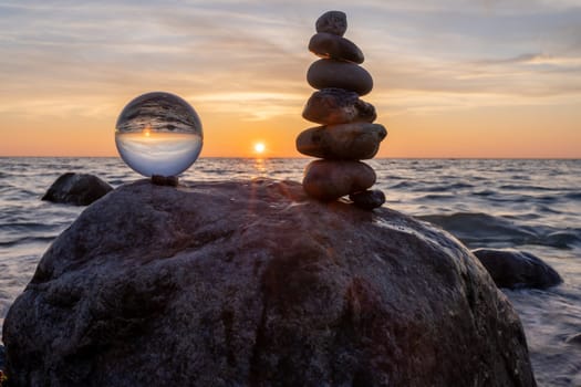 Stone pyramids and glass sphere on the dreamy Baltic Sea sand beach on Rügen for the spectacular sunset
