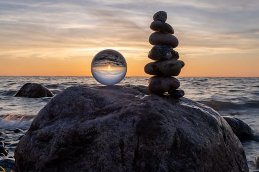 Stone pyramids and glass sphere on the dreamy Baltic Sea sand beach on Rügen for the spectacular sunset