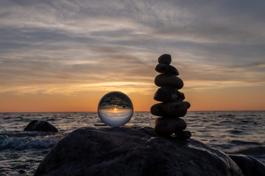 Stone pyramids and glass sphere on the dreamy Baltic Sea sand beach on Rügen for the spectacular sunset