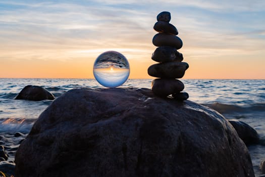 Stone pyramids and glass sphere on the dreamy Baltic Sea sand beach on Rügen for the spectacular sunset