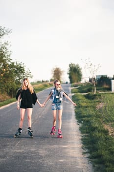 Teenage smiling happy girls having fun rollerskating, spending time together on summer day