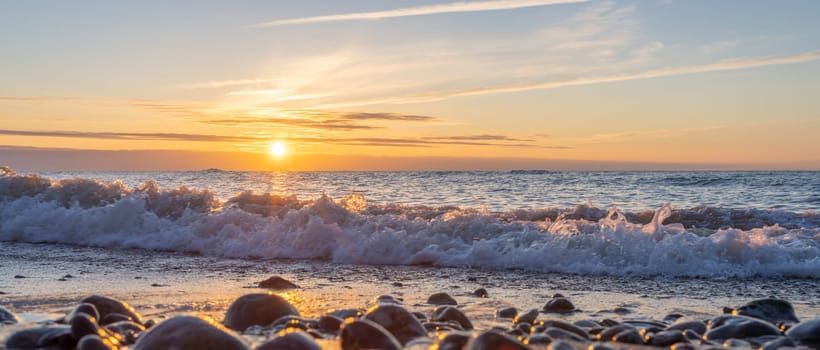 orange, sunset between rocks in the sea of the Baltic Sea near Dranske on the island of Rügen-	Beautiful sunset over the sea with waves and rocks in the foreground