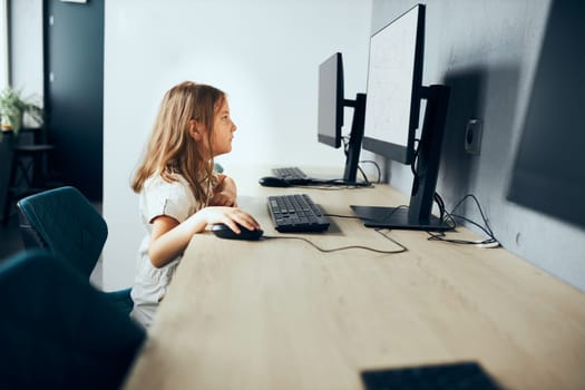 Engaged absorbed schoolgirl learning to use technology in classroom at primary school. Child using computer on elementary computer science class. Smart little girl learning programming and coding at school. Child solving riddles on personal computer. Back to school