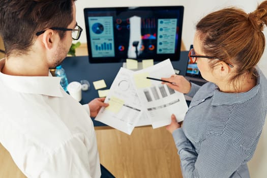 Business colleagues discussing financial data working together in office. People entrepreneurs working with charts and tables on computer. Two people working together. Workmates talking about project