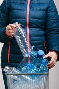 Woman throwing out used plastic bottles and packagings in trash bin. Collecting empty plastic squashed bottles in blue bag. Plastic waste to recycling. Concept of plastic pollution and too many plastic waste