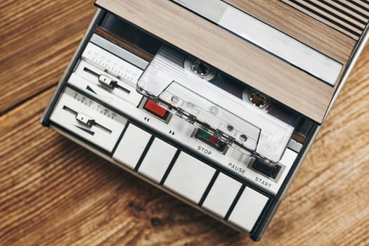 Compact cassette tapes and cassette recorder on wooden table. Retro music style. 80s music party. Vintage style. Analog equipment. Stereo sound. Back to the past