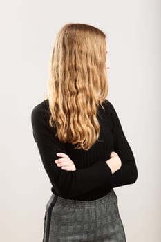 Portrait of profile long hair pretty cheerful young woman holding arms crossed standing over a grey plain background