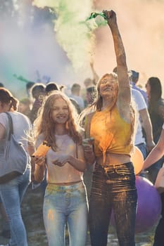 Portrait of happy smiling young girls with colorful paints on faces and clothes. Two friends spending time on holi color festival