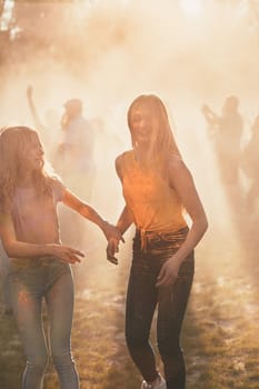Portrait of happy smiling young girls with colorful paints on faces and clothes. Two friends spending time on holi color festival