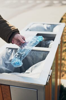 Woman throwing a plastic bottle to trash. Plastic waste to recycling. Concept of plastic pollution and recycling plastic waste. Environmental issue. Environmental damage. Real people, authentic situations