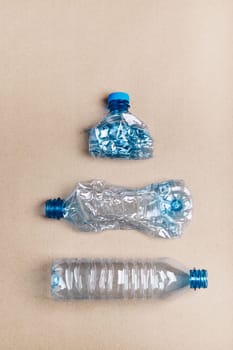 Squashed plastic bottles over cardboard background. Collecting plastic waste to recycling. Concept of plastic pollution and too many plastic waste. Copy space at the top