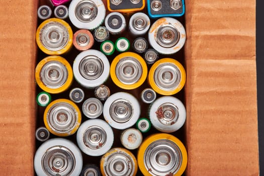 Discharged batteries in cardboard box. Collecting used batteries to recycle. Waste disposal and recycling. Copy space for text