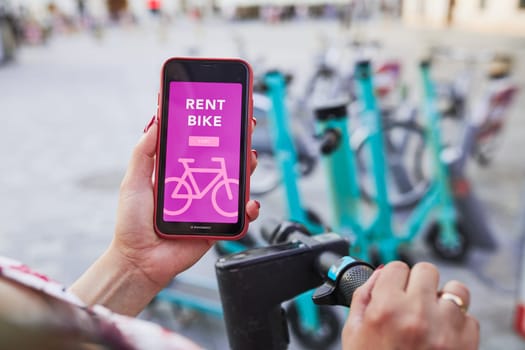 Renting bike using rental app on smartphone. Using bike sharing city service. Paid rent of electric scooter. Using mobile phone to rent and pay for public eco transport. Bike sharing city station. Ecological transport alternative. 24/7 rental mobile service