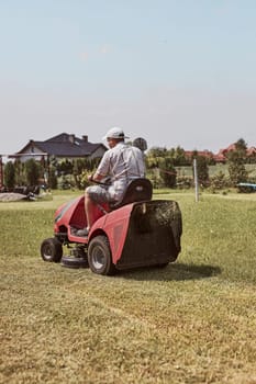 Man mowing his lawn using riding lawnmower. Man maintaining grass in his garden beside house