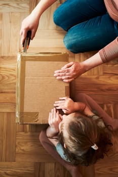 Woman unpacking a cardboard box parcel in room at home. Little girl waiting for opening a gift in package