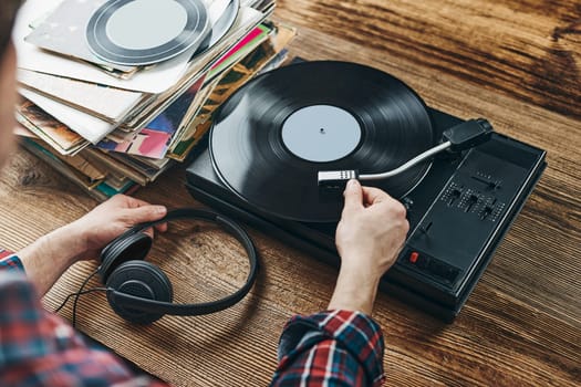 Man listening to music from vinyl record. Playing music from analog disk on turntable player. Enjoying music from old collection. Relaxing at home. Retro and vintage. Music passion