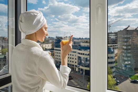 Back view at young woman standing on balcony with closed eyes
