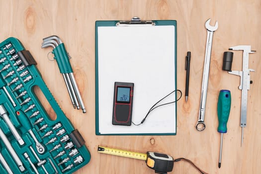 Workshop table with many tools. Wrench, spanner, calliper and ratchet with many attachments. Clipboard with white paper. Work tools. Universal tool set. Professional equipment. Background. Copy space