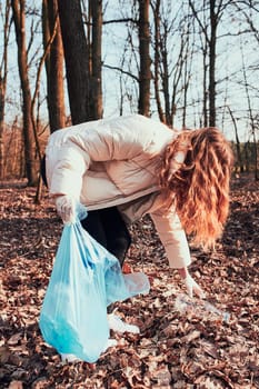 Young woman cleaning up a forest. Volunteer picking plastic waste to bags. Concept of plastic pollution and too many plastic waste. Environmental issue. Environmental damage. Responsibilitiy for environment. Real people, authentic situations