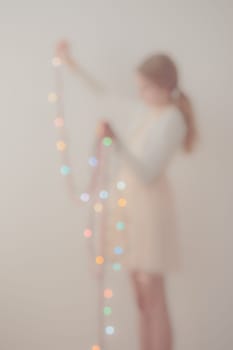 Out of focus portrait of young girl unwrapping colorful Christmas lights