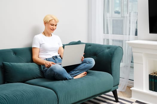 Middle aged woman chatting with friend in her new apartment online. Concept of clever ageing and adaptation to new reality.