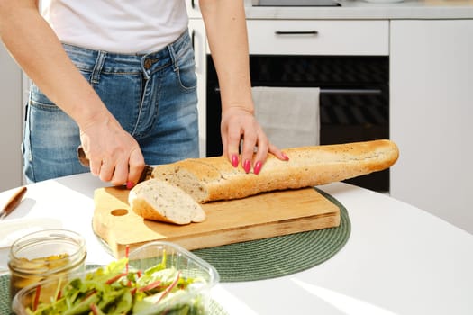 Closeup view of cutting fresh baguette on slices